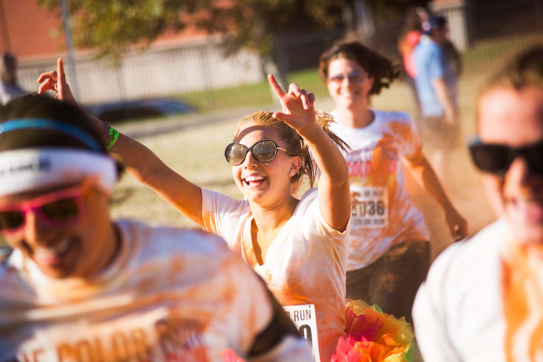 A woman wearing sunglasses, arms raised in cheer against a bright background, embodying positivity and empowerment.