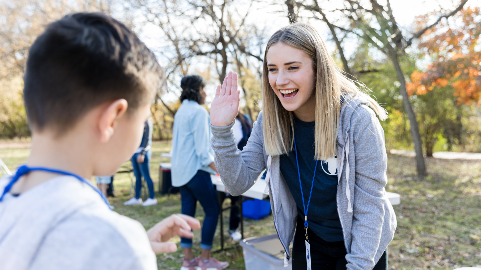 A smiling volunteer giving a high-five to a child at a community outreach event, promoting engagement and positive interactions.