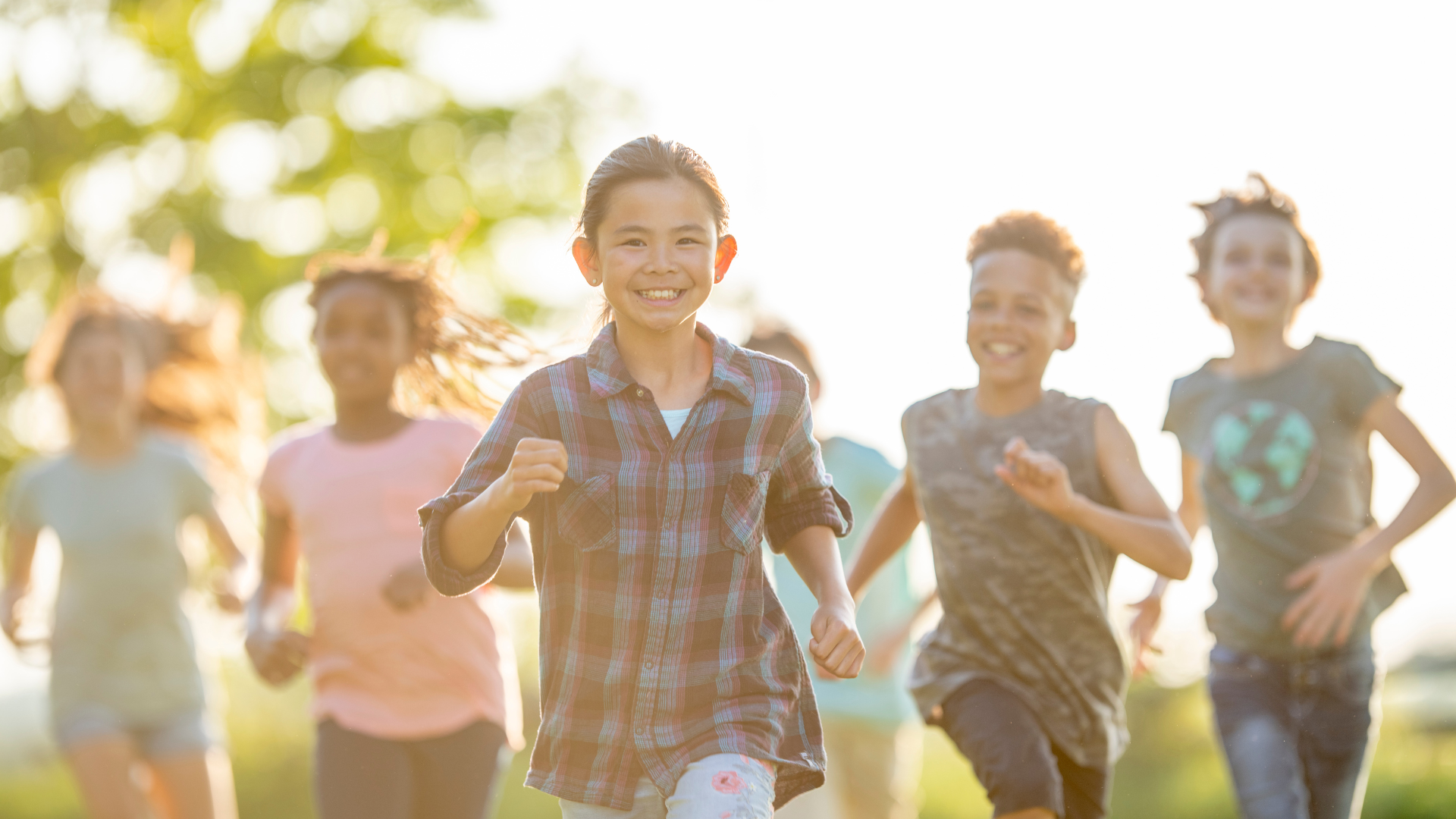 Joyful children running together in a park, symbolizing health, vitality, and community in youth services.