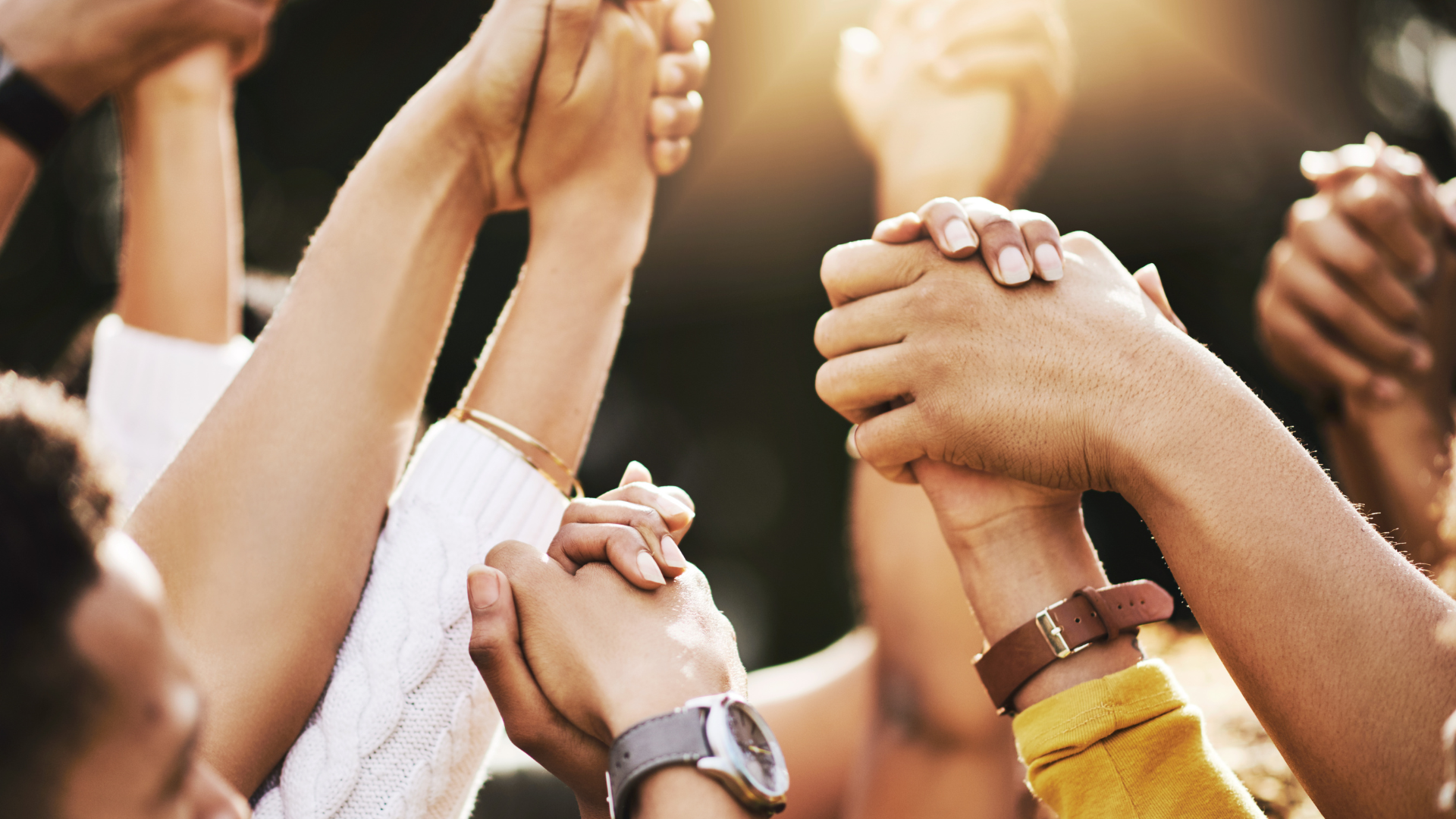 A close-up view of diverse hands clasped together in a show of unity and support within the community.