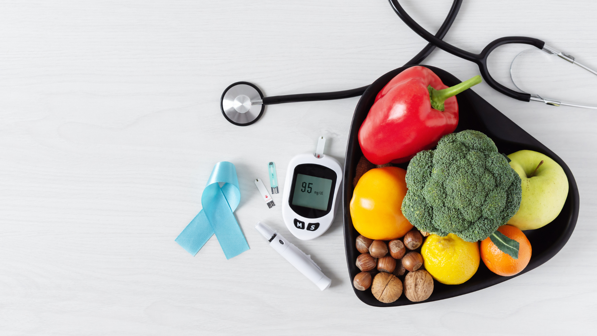 A heart-shaped plate filled with healthy foods flanked by diabetes monitoring equipment and a blue ribbon, symbolizing proactive health management and diabetes prevention.