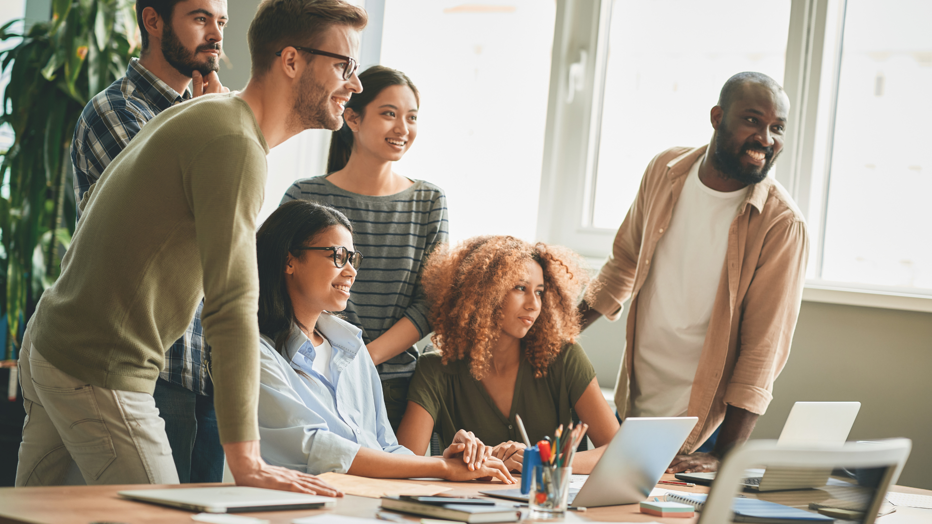 Group of diverse employees collaborating over a project in a brightly lit conference room.