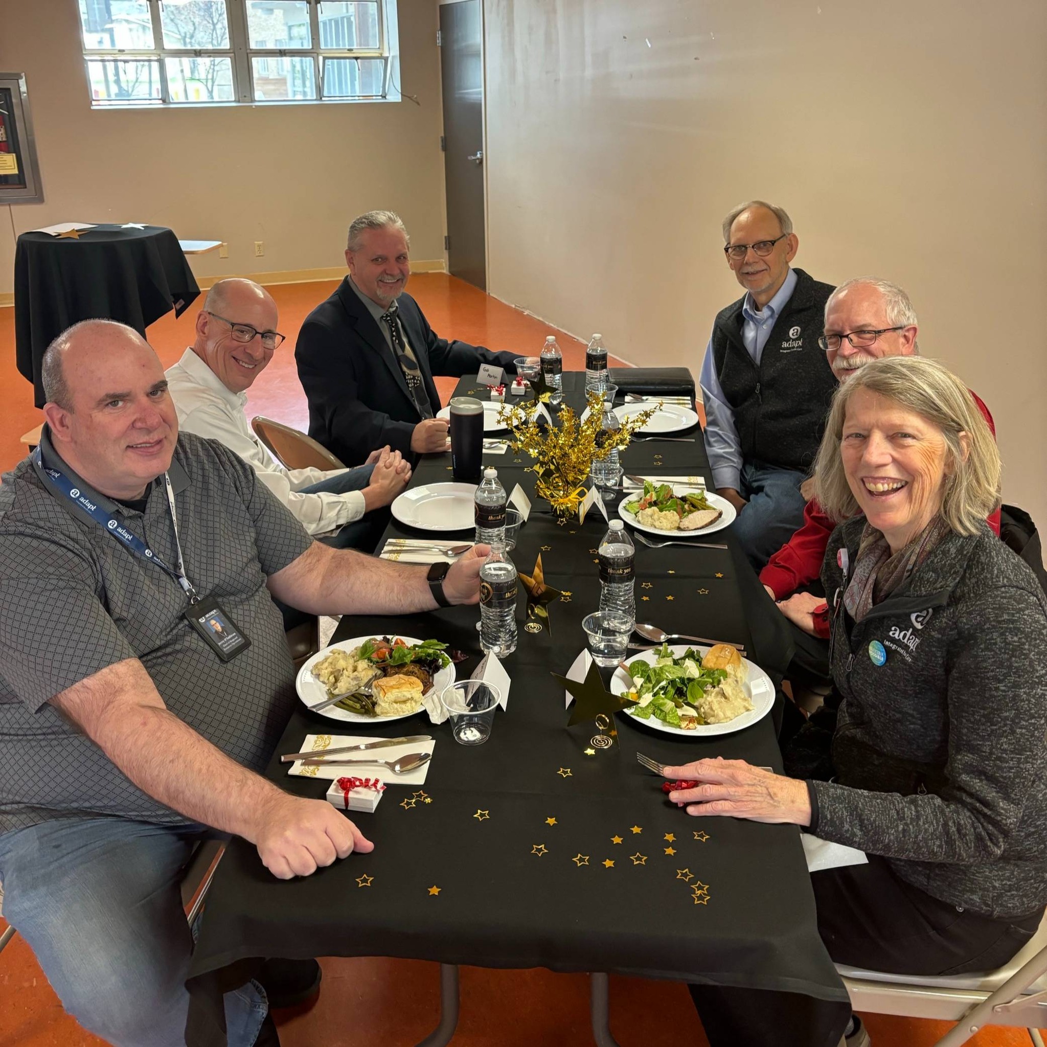 Years of Service Recognition 2024: A group of Adapt Integrated Health Care employees, including executives, seated at a decorated table enjoying a meal, celebrating years of service.