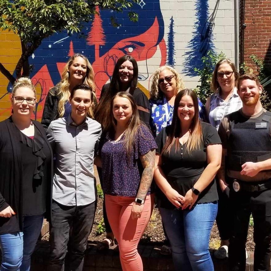 Roseburg OTP: A group of Adapt Integrated Health Care employees standing outside in front of a mural, smiling for a group photo.