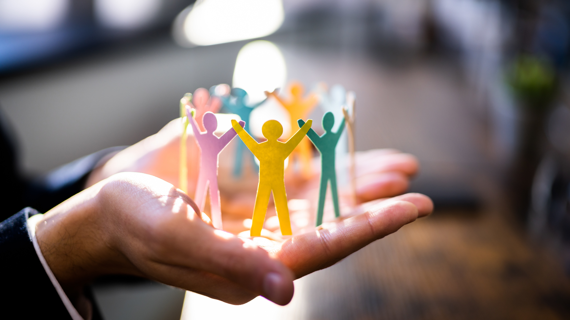 A hand holding colorful paper figures in a circle, symbolizing unity and collaborative leadership at Adapt Integrated Health Care.